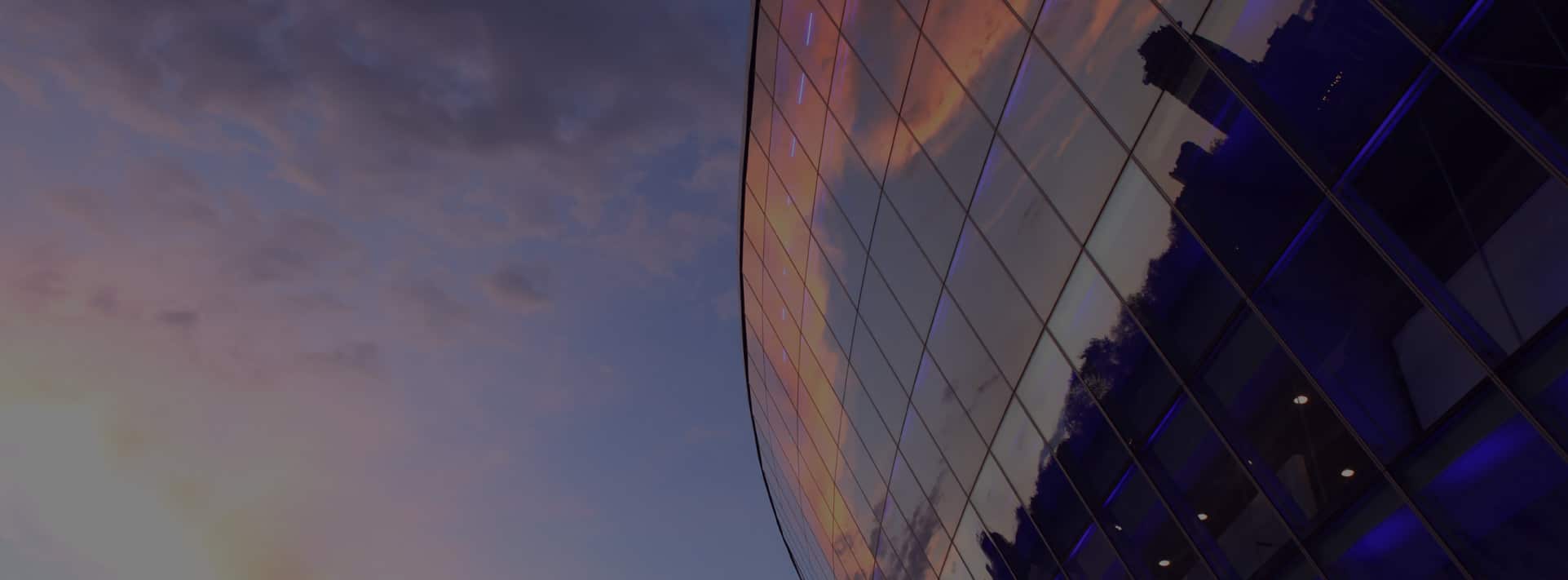 Glass front of building against a blue and red sky